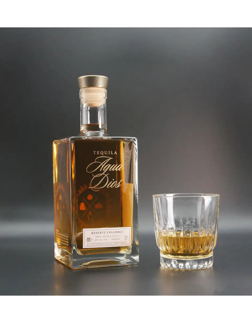 Tequila bottle and glass with Agua de Dios on a gray background