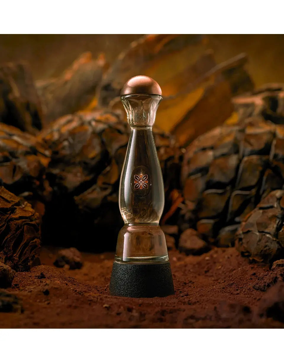 Glass pepper grinder with copper top on a textured brown background