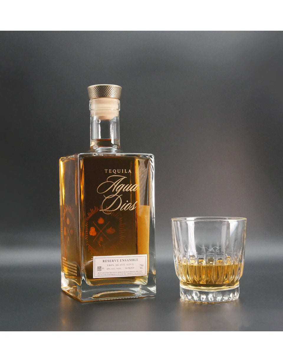 Tequila bottle and glass with Agua de Dios on a gray background