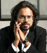 Man in a suit sitting on a bench with a neutral background